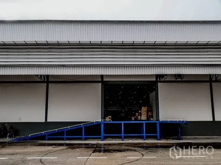 Warehouse for rent in Mueang Samut Prakan, Samut Prakan - Warehouse exterior with dock-high loading bay and blue ramp for truck access.