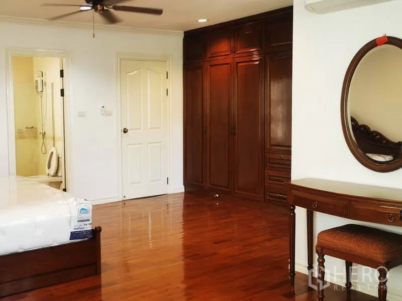 Detached House for rent in Mueang Samut Prakan, Samut Prakan - Spacious bedroom with built-in wooden wardrobes, vanity and an ensuite bathroom.