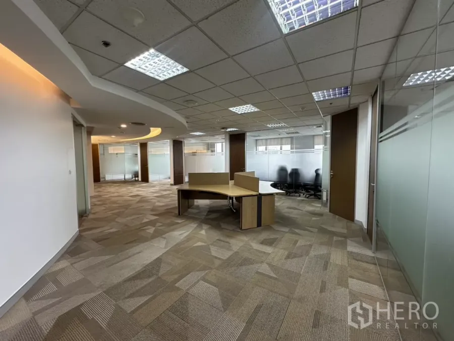 Office Space for rent in Watthana, Bangkok - Open-plan workspace with a central desk, glass-partitioned rooms and grid ceiling lights.