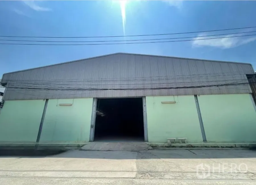 货栈 出租在Bang Phli, Samut Prakan - 金属屋顶仓库外观，中央大门开启，蓝天下采光充足。