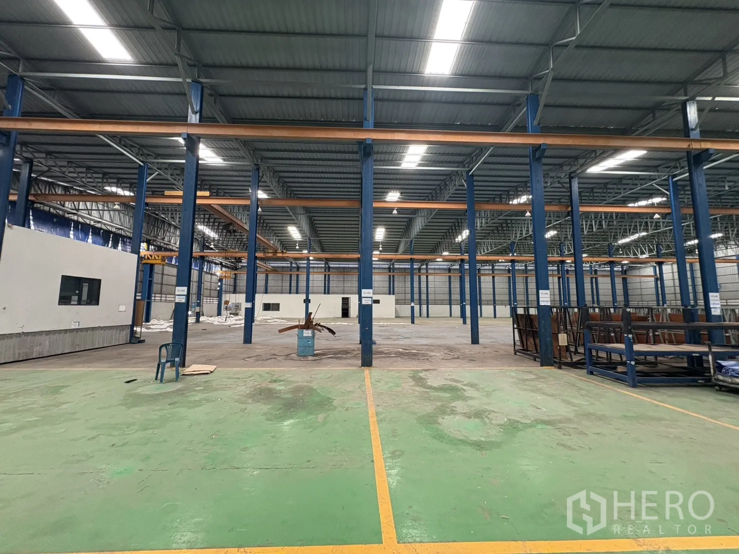 Factory for rent in Phra Pradaeng, Samut Prakan - Spacious green and gray floor areas separated by safety fencing.