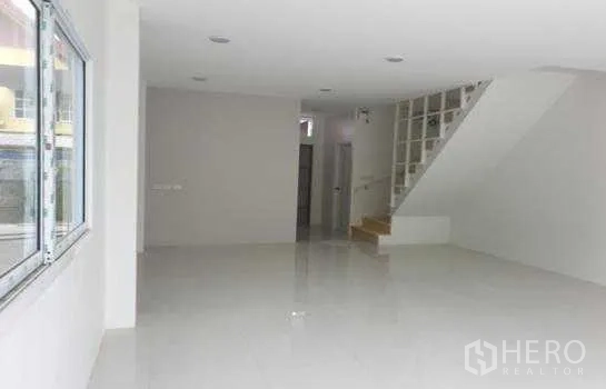 Warehouse for rent in Prawet, Bangkok - Open warehouse office area with staircase, storage niche and white tiled flooring.