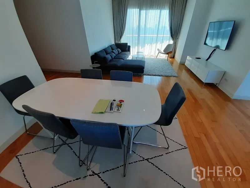 Condominium for rent in Khlong Toei, Bangkok - Dining space overlooking cozy lounge and wall-mounted TV.