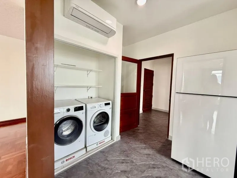 Condominium for rent - Laundry nook with Bosch washer and dryer next to a refrigerator and doorway.