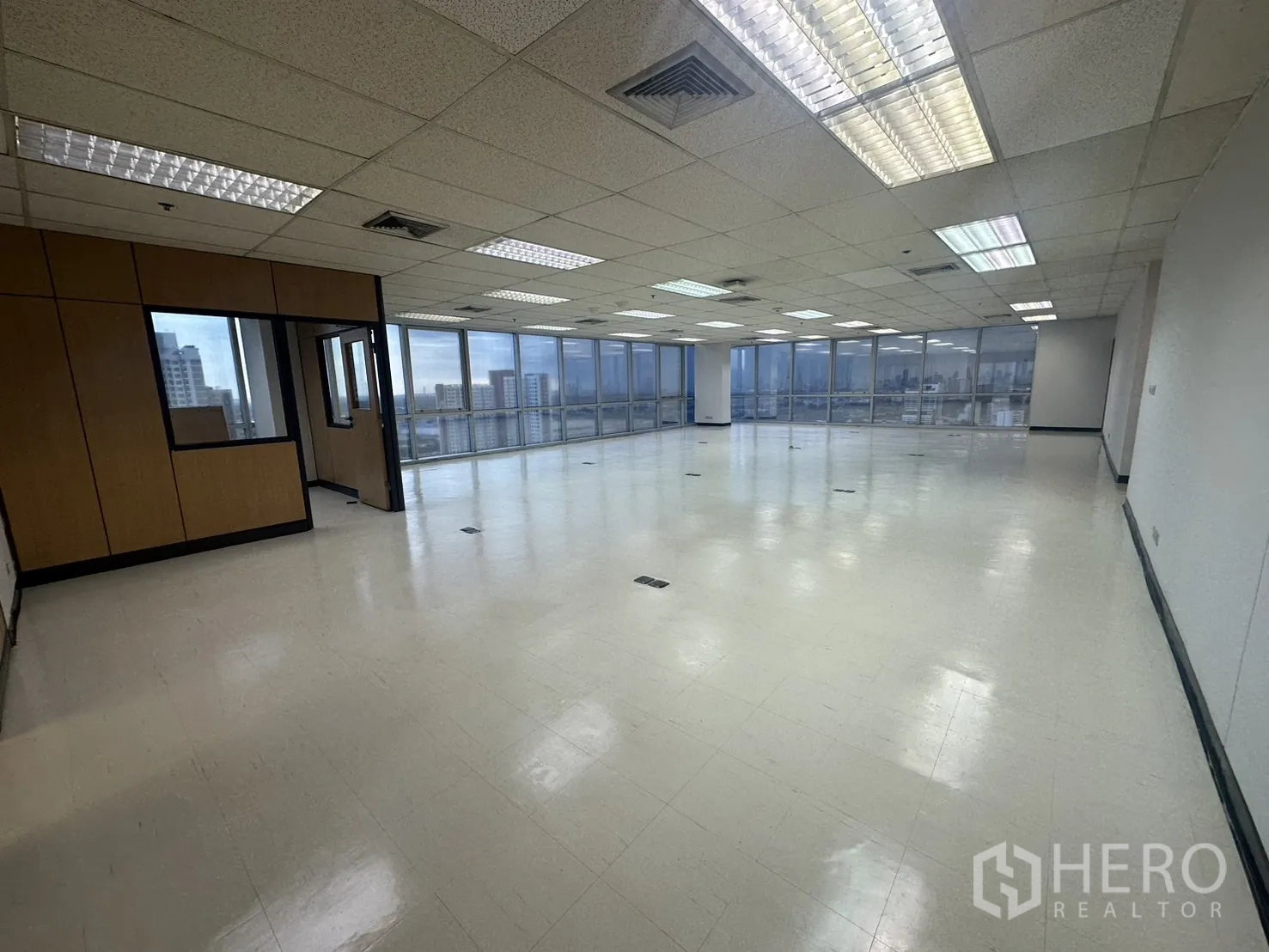 Office Space for rent - Open-plan office with full-height windows, skyline views, and drop-ceiling lights in Phra Khanong.
