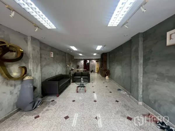 Shophouse for rent in Bang Rak, Bangkok - Long open-plan retail space with ceiling lights, concrete walls and a seating set.