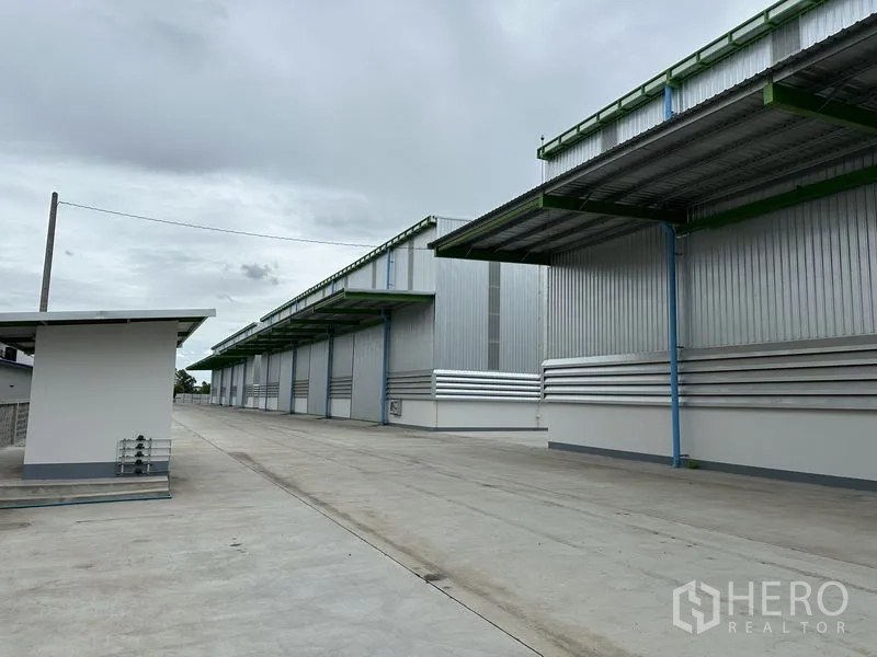 Warehouse for rent in Wang Noi, Phra Nakhon Si Ayutthaya - Row of metal warehouses with covered loading bays along a spacious internal driveway.