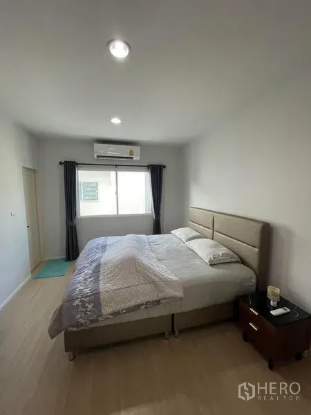 Townhouse for rent in Suan Luang, Bangkok - Bright master bedroom with king bed, air conditioner, window and light wood flooring.