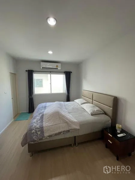 Townhouse for rent in Suan Luang, Bangkok - Bright master bedroom with king bed, air conditioner, window and light wood flooring.