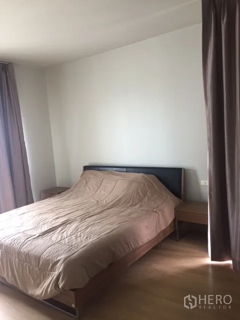 Condominium for rent in Bangkok - Master bedroom with double bed, bedside tables and a large window with curtains.