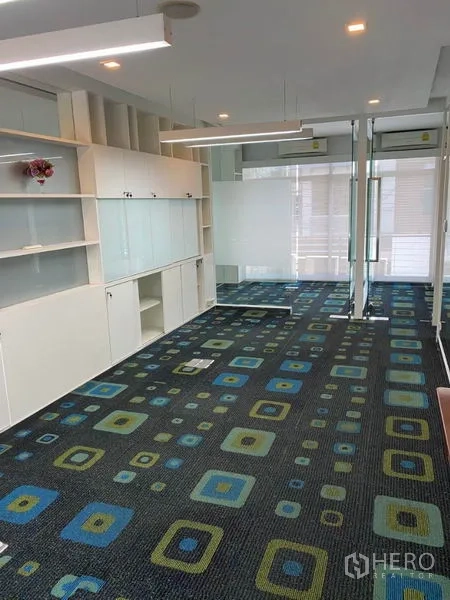 Home Office for rent in Wang Thonglang, Bangkok - Open-plan office with colorful patterned carpet, built-in storage and glass walls.
