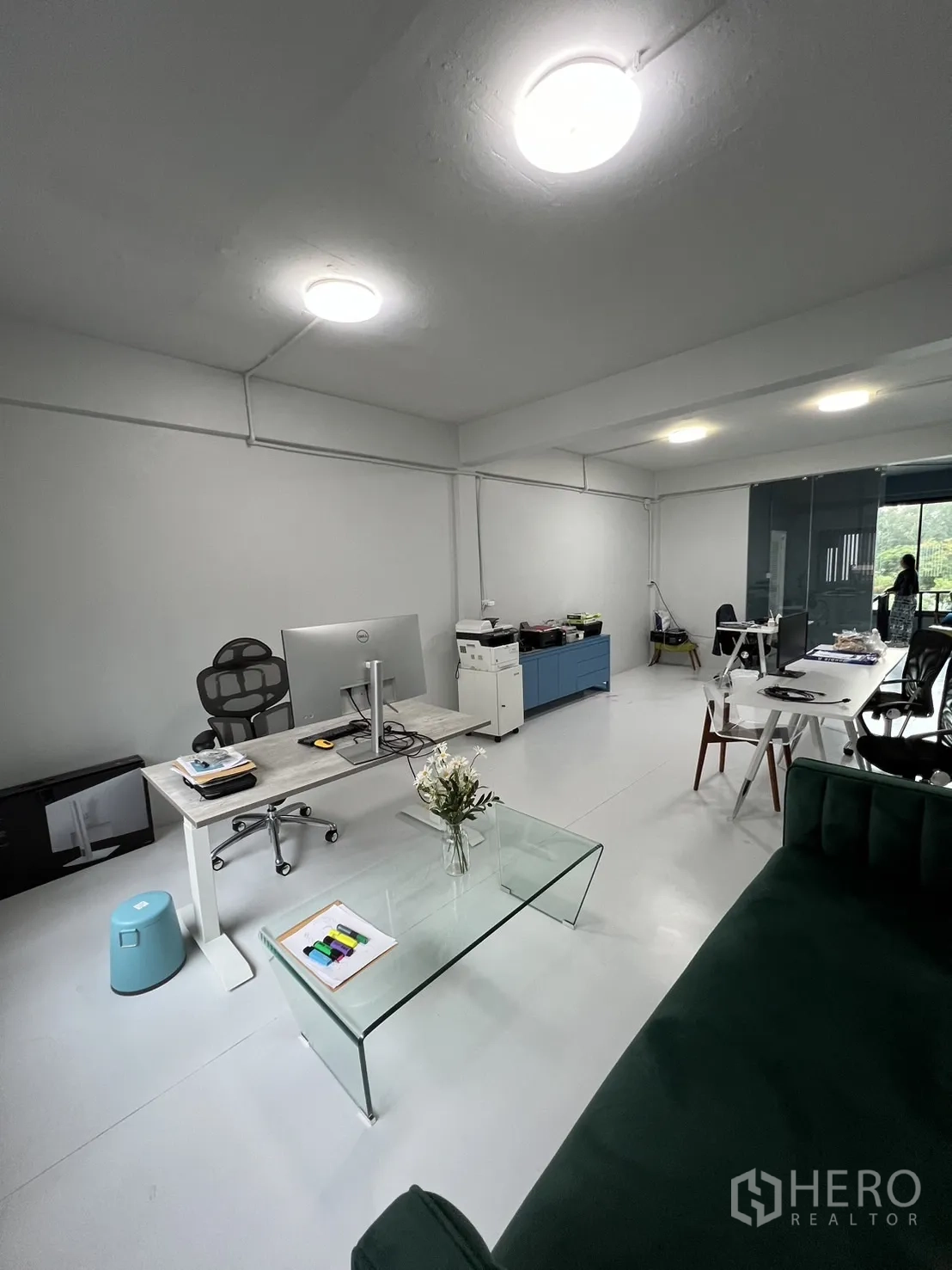 Shophouse for rent or sale in Watthana, Bangkok - Modern office floor with desks, a glass coffee table and large windows.