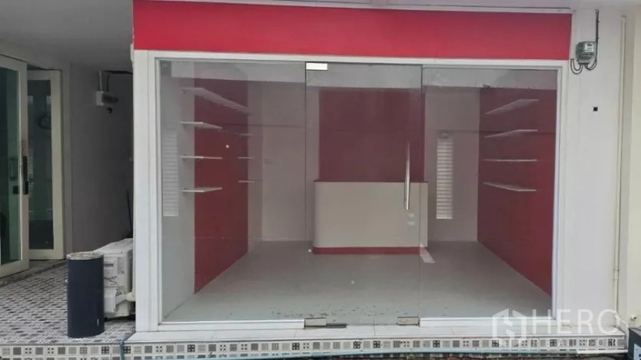 Retail Space for rent in Watthana, Bangkok - Street-facing shopfront with full-glass facade, red sign panel, and interior display shelves visible.