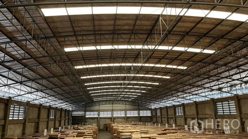 Factory for rent or sale in Pathum Thani - High-clearance warehouse interior with steel truss roof and skylights.
