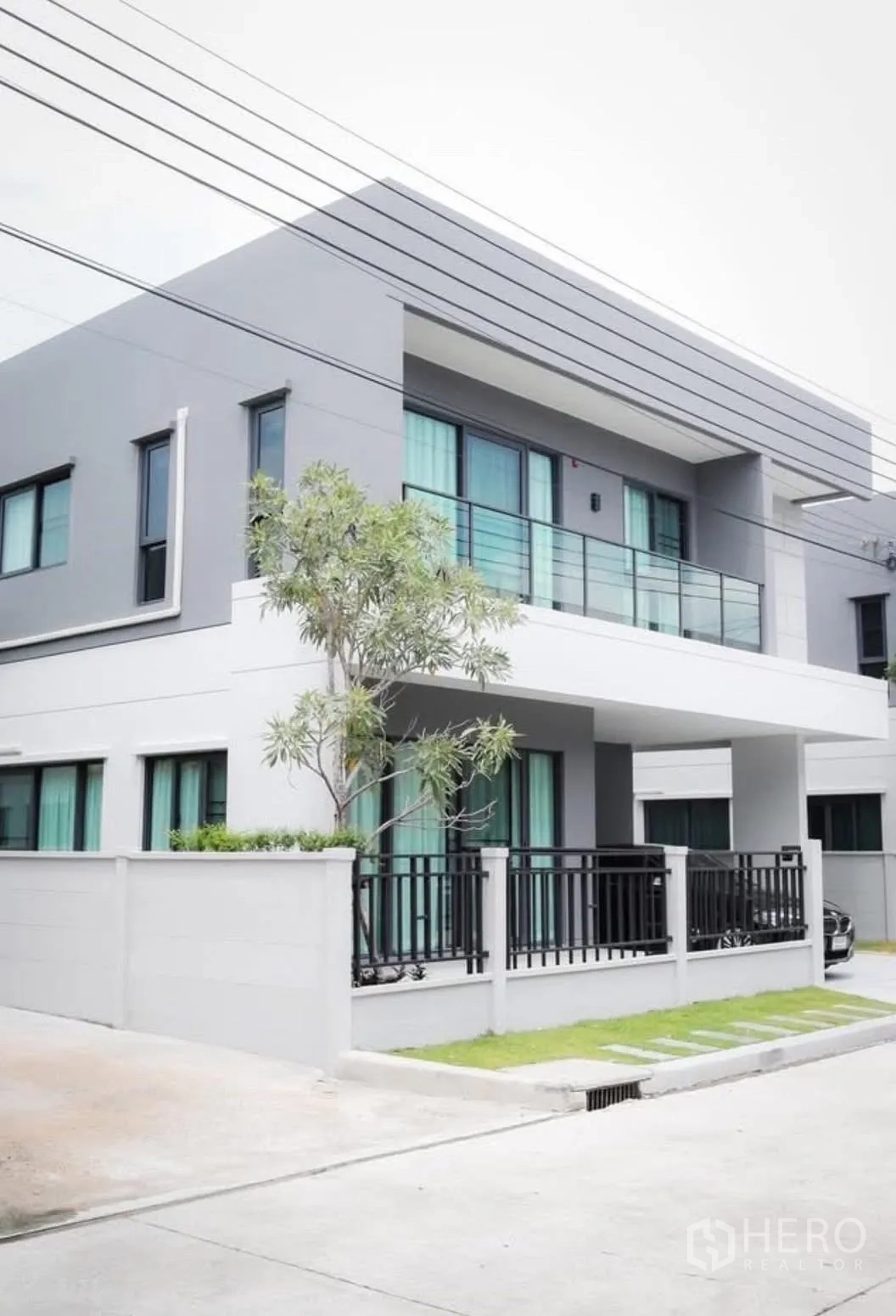 Detached House for rent in Bang Phli, Samut Prakan - Corner view of a contemporary detached house with balcony and gated fence.
