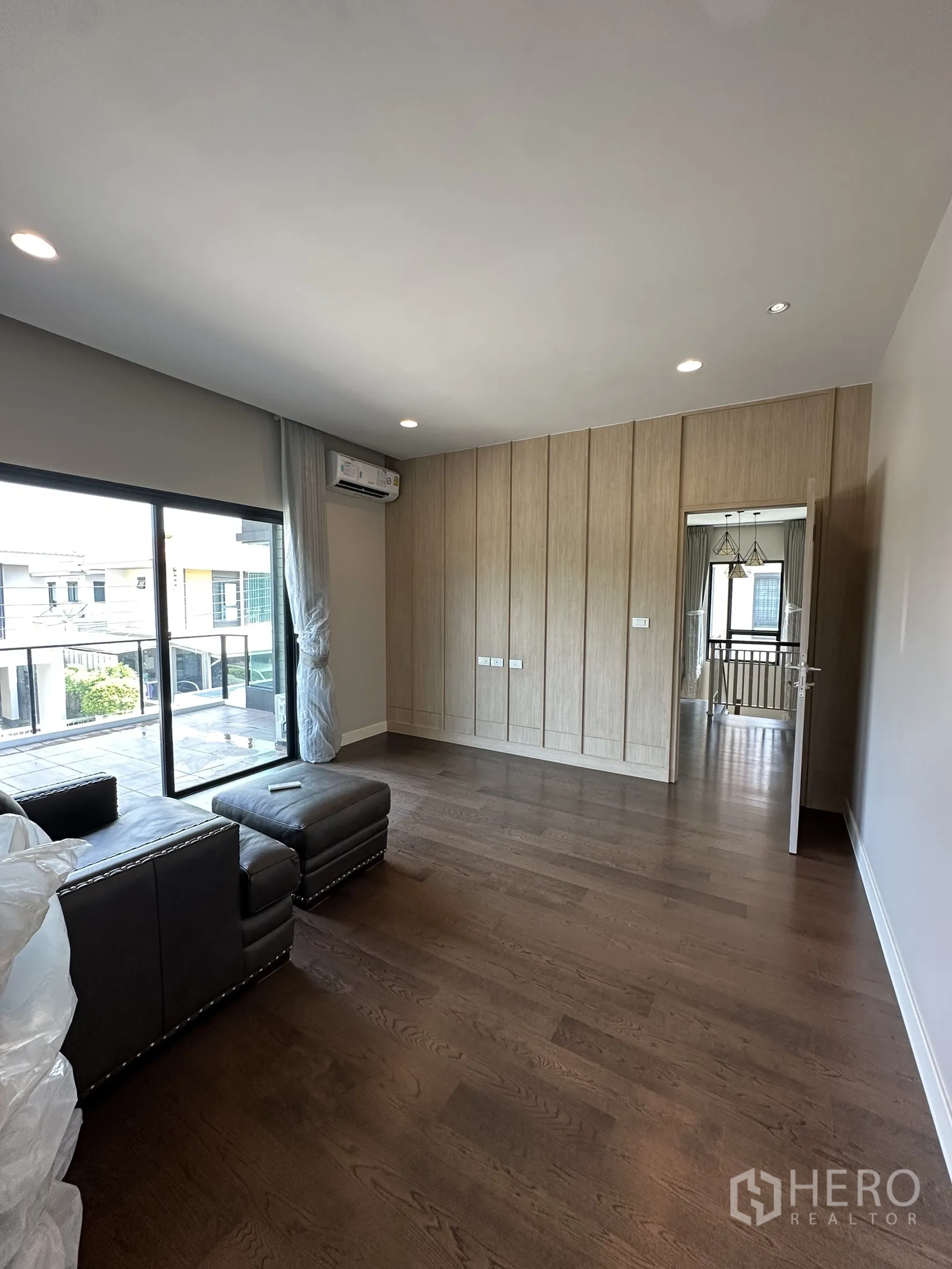 Detached House for sale in Lam Luk Ka, Pathum Thani - Upper floor family room or bedroom with dark wood flooring and access to the balcony.