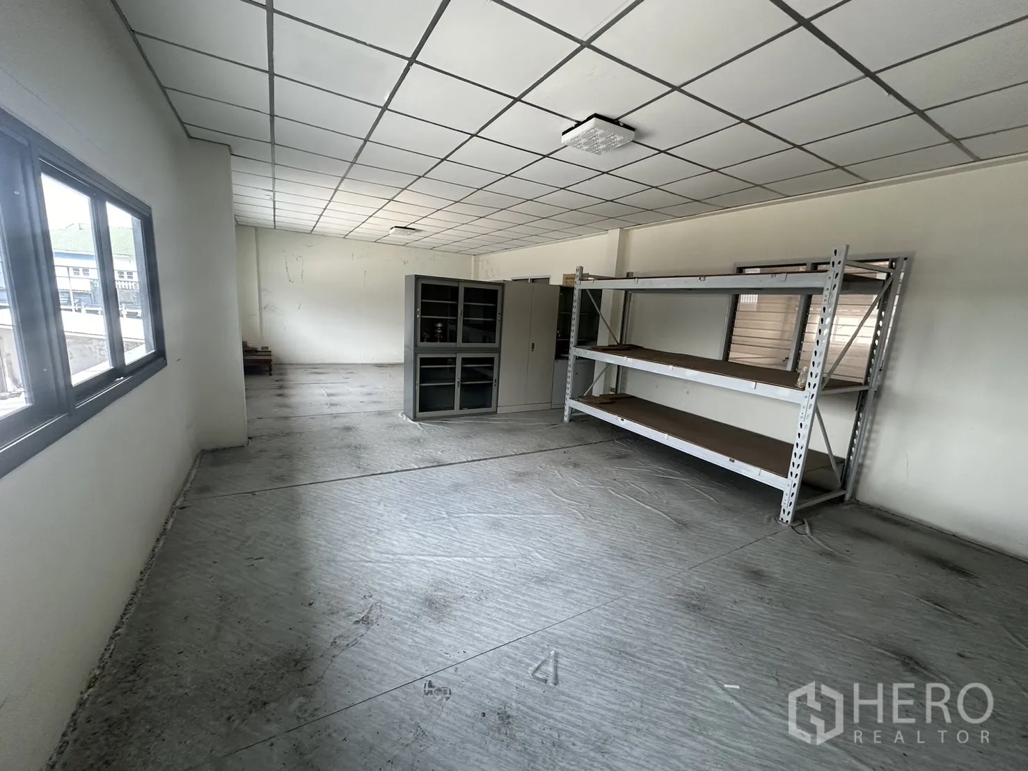 Factory for rent or sale in Prawet, Bangkok - Additional storage room with metal shelving and grid ceiling.