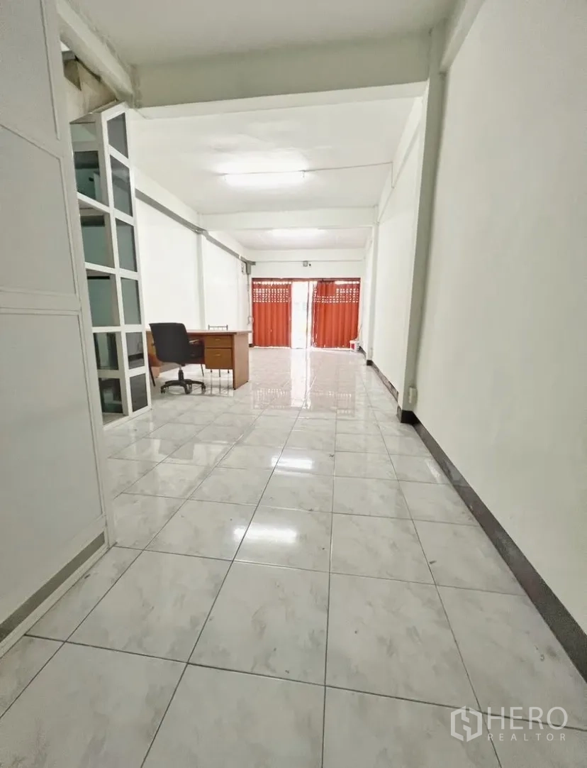 Shophouse for rent in Suan Luang, Bangkok - Long open-plan ground floor with glossy tiles and glass partition.