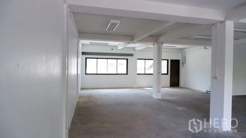 Office Space for rent in Watthana, Bangkok - Open workspace showing windows, ceiling lights, and an interior door.