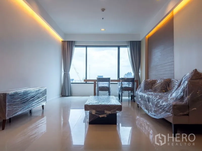 Condominium for rent or sale in Pathum Wan, Bangkok - Open‑plan living and dining area with large picture window and glossy floors.