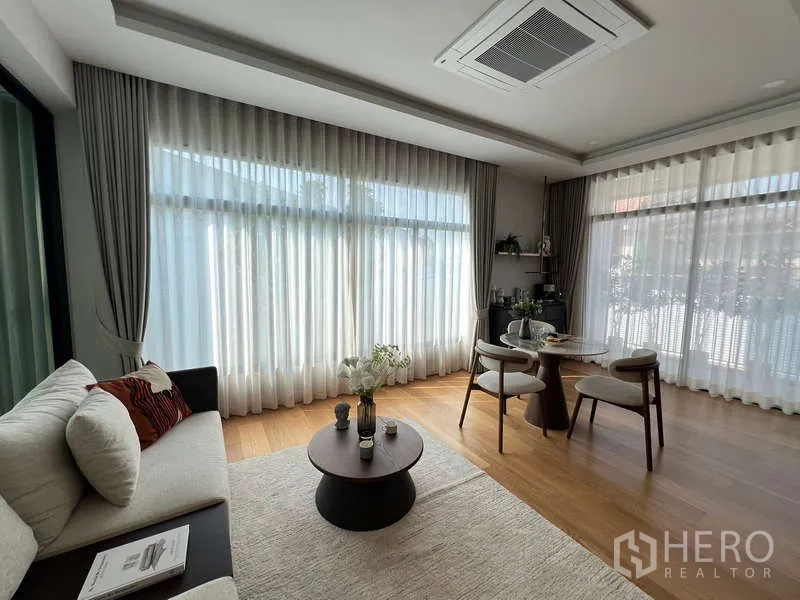 独立式住宅 出售在Suan Luang, Bangkok - 转角起居区，沙发与圆形餐桌，环景窗