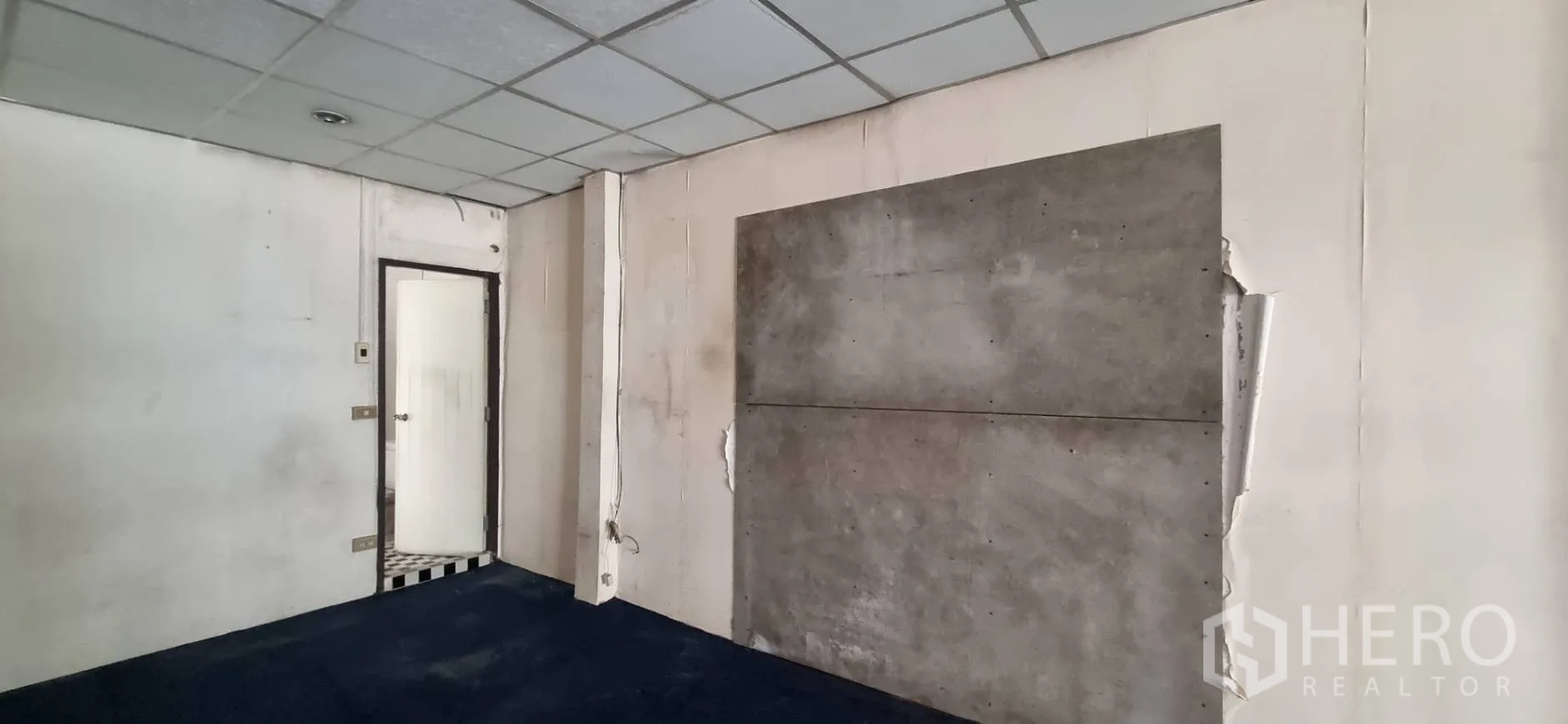 Shophouse for rent or sale in Bangkok - Upper-level corner with door to a bathroom and a concrete feature wall.