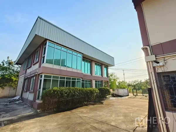 货栈 出租或出售在Min Buri, Bangkok - 转角玻璃办公楼连接仓库，大面积窗户，混凝土院场与绿色大门。