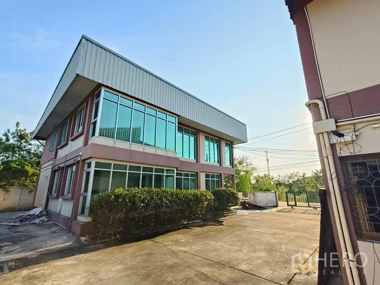 货栈 出租或出售在Min Buri, Bangkok - 转角玻璃办公楼连接仓库，大面积窗户，混凝土院场与绿色大门。