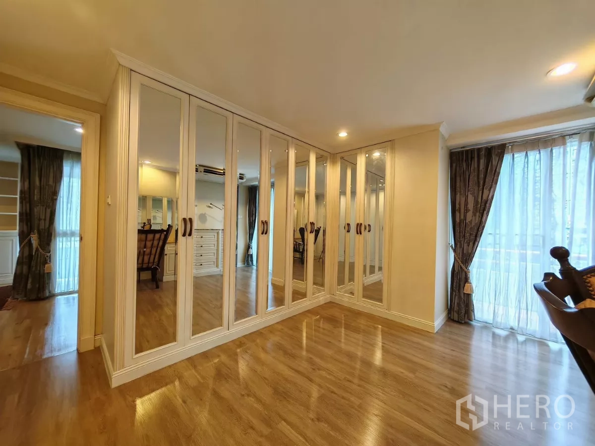 Condominium for rent in Pathum Wan, Bangkok - Dressing room with mirrored wardrobes and floor-to-ceiling curtains.