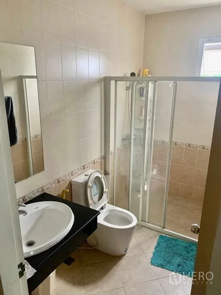 Detached House for rent in Prawet, Bangkok - Tiled bathroom with sliding glass shower, toilet, and single-sink vanity.