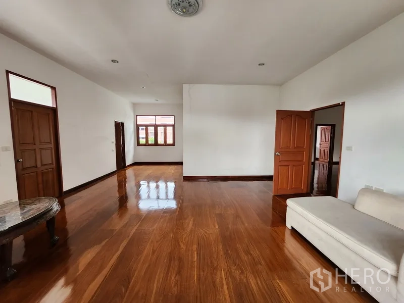 Detached House for rent in Prawet, Bangkok - Second‑floor lounge with sofa, hardwood floors and light from a large window.