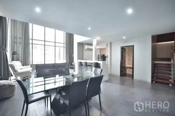Condominium for rent in Khlong Toei, Bangkok - Open-plan dining area with glass table for six next to the living room and breakfast bar.