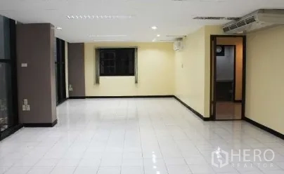 办公空间 出租在Bang Rak, Bangkok - 开放式办公区，白色地砖，吊顶灯，多个窗户与通往内室的门。