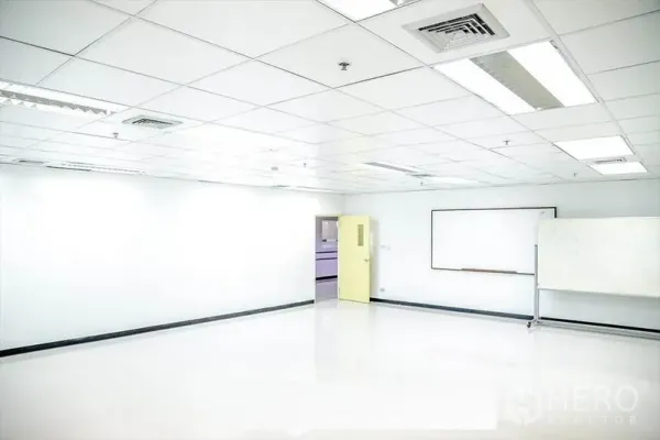 Office Space for rent in Bang Na, Bangkok - Spacious office interior with grid ceiling lights, a yellow door, and a wall-mounted whiteboard.