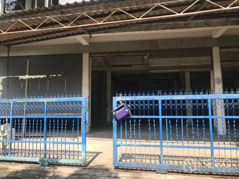 คลังสินค้า ให้เช่าในBueng Kum, Bangkok - ด้านหน้าโกดังพร้อมรั้วเหล็กสีน้ำเงิน ประตูม้วน และพื้นที่โหลดสินค้ามีหลังคา