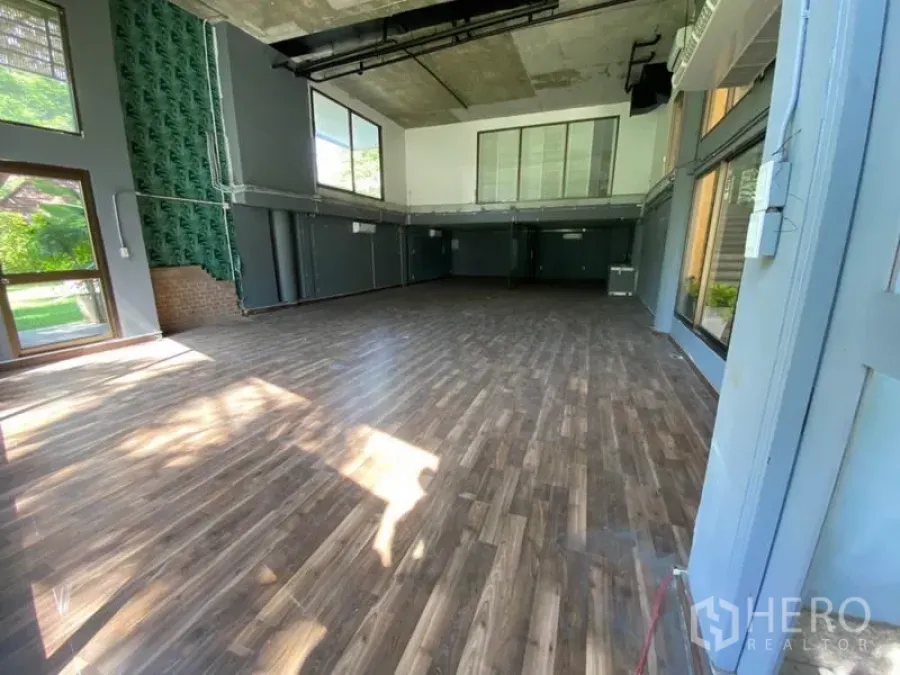 Retail Space for rent in Watthana, Bangkok - Spacious double-height retail unit with wood flooring, large windows and a mezzanine.