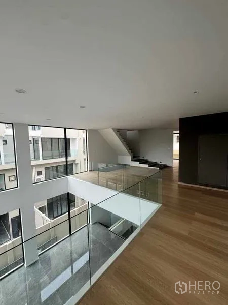 Home Office for rent or sale in Lat Phrao, Bangkok - Mezzanine level with glass balustrade overlooking the double-volume hall and stair.