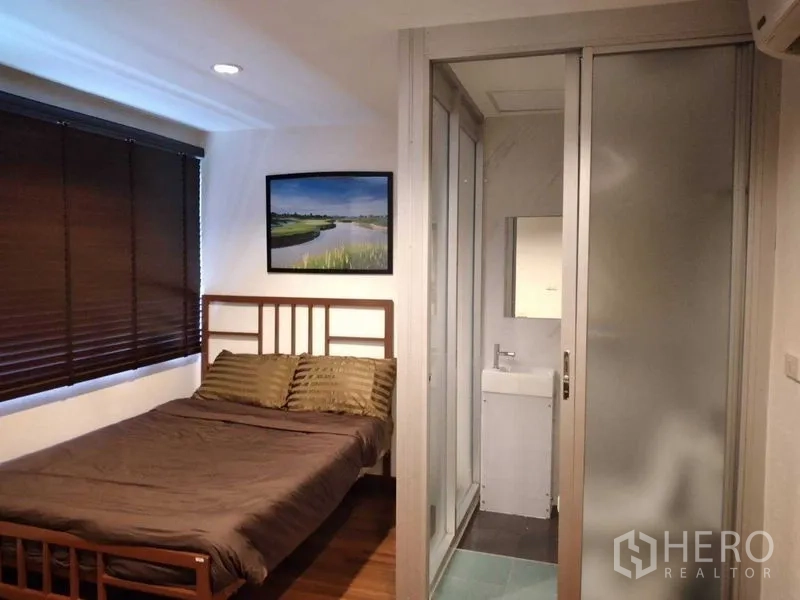 Shophouse for rent in Watthana, Bangkok - Bedroom with double bed, blackout blinds, and en-suite bathroom with sliding glass door.