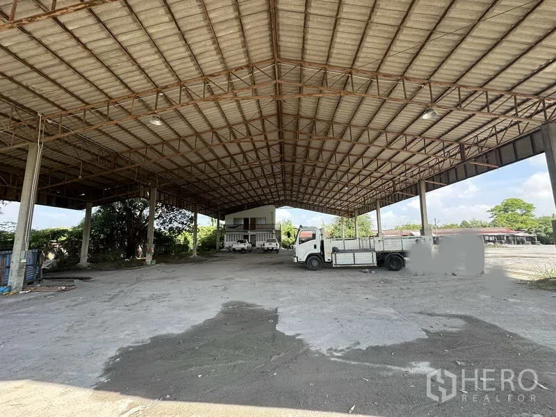 Factory for rent in Phra Nakhon Si Ayutthaya - Large covered loading area with high roof, truck parking, and an office block at the rear.