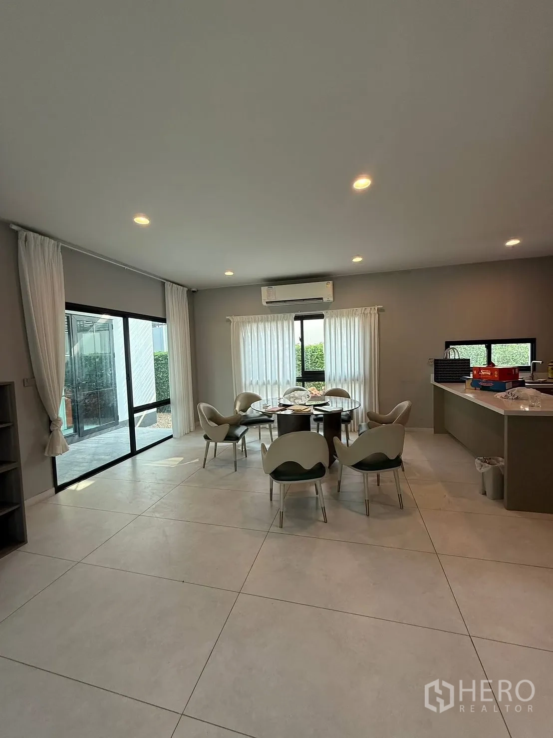 Detached House for rent in Bang Kapi, Bangkok - Open-plan dining and living space with round table, large tiles and sliding glass doors to the garden.