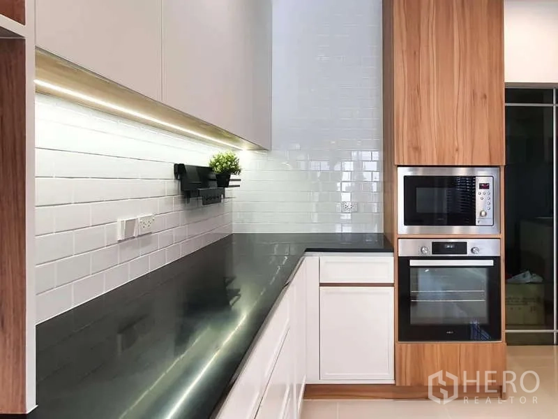 Detached House for rent in Sathon, Bangkok - Built-in modern kitchen with black stone countertop, white subway tiles, and stacked stainless-steel ovens.