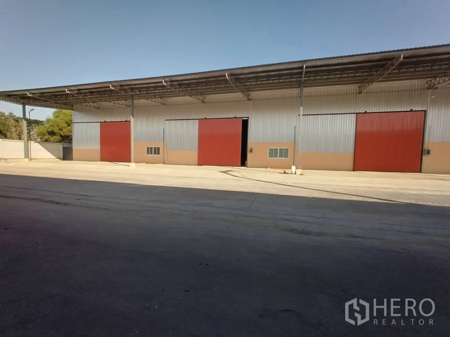 Warehouse for rent in Khlong Luang, Pathum Thani - Row of warehouse bays with a high roof structure and a wide driveway for trucks in front.