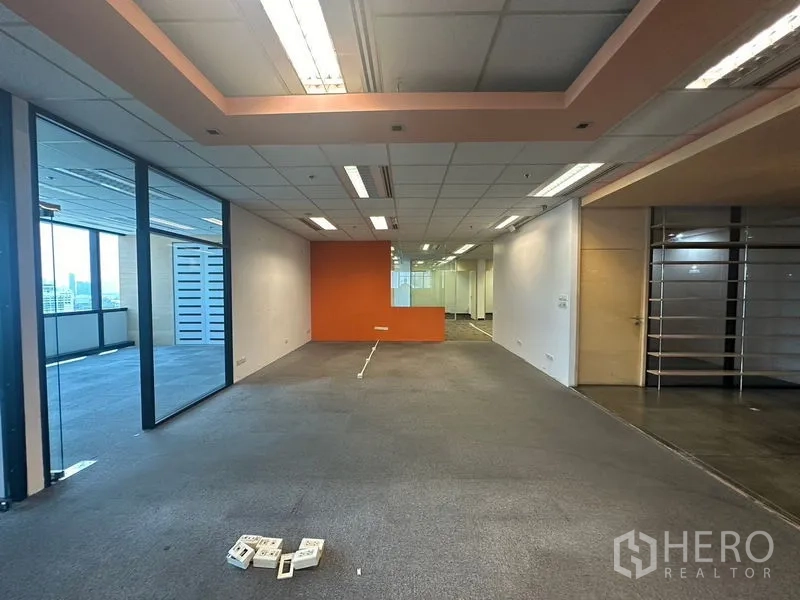 Office Space for rent in Khlong Toei, Bangkok - Open office area with orange accent wall, recessed lights, and adjoining meeting rooms.