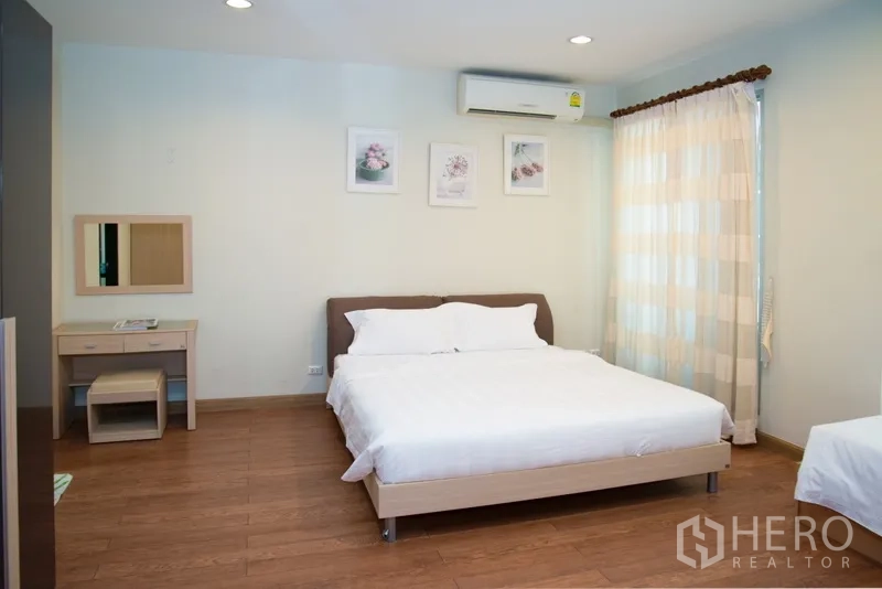Condominium for rent in Khlong Toei, Bangkok - Spacious bedroom with double bed, dressing table, air conditioner and soft curtains.