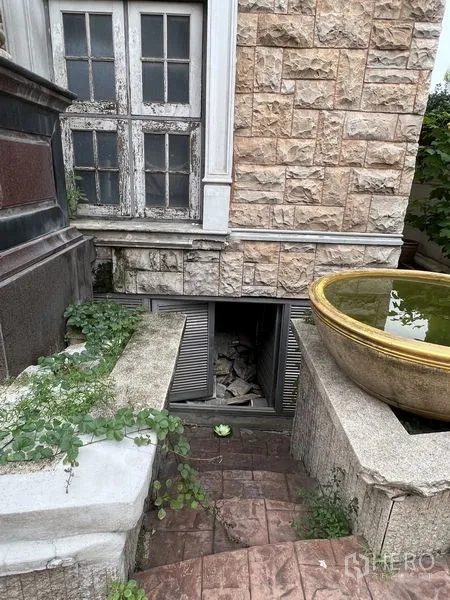 Home Office for rent in Huai Khwang, Bangkok - Basement access hatch beneath stone wall with planter and greenery.