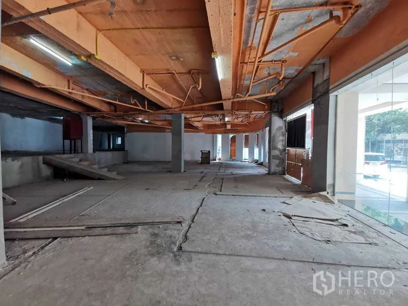 Retail Space for rent in Khlong Toei, Bangkok - Wide retail floor with glass display windows, ramp access, and raw concrete slab.