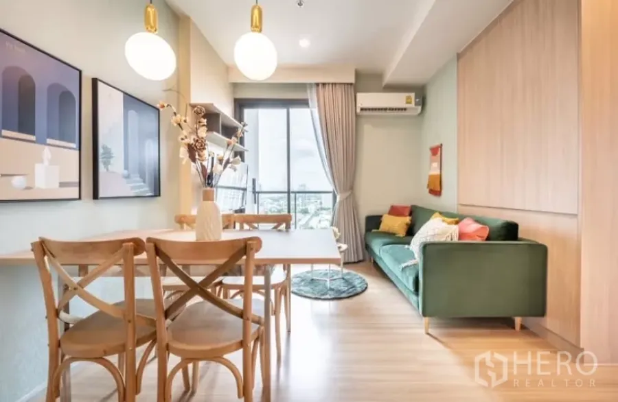 Condominium for rent in Chatuchak, Bangkok - Bright living and dining area with wood floors, green sofa, pendant lights and a balcony city view.