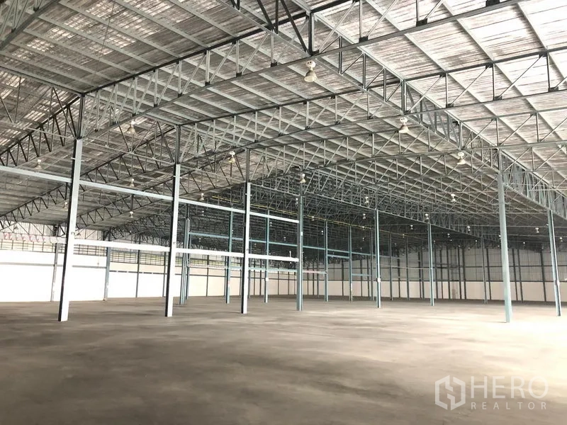 Warehouse for rent in Bang Phli, Samut Prakan - Spacious warehouse interior in Bang Phli, Samut Prakan with high steel truss roof and concrete floor.