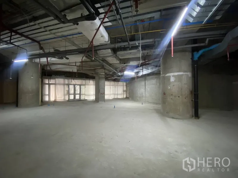 Retail Space for rent - Spacious corner interior with structural columns and distant glazed entry providing natural light.