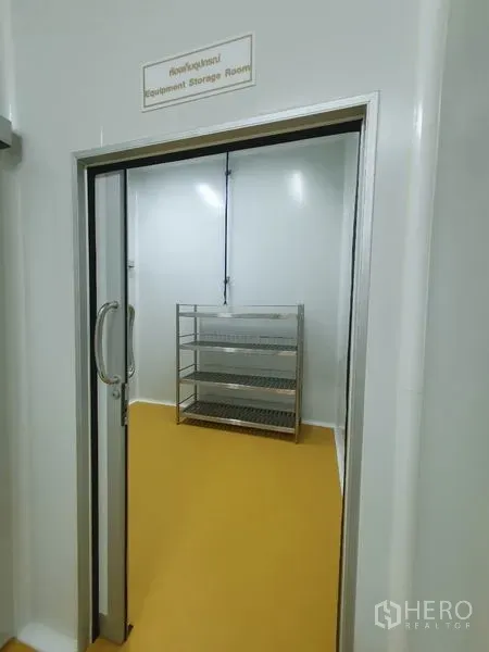 Factory for sale in Lam Luk Ka, Pathum Thani - Equipment storage room with stainless steel shelving seen through a sliding door.